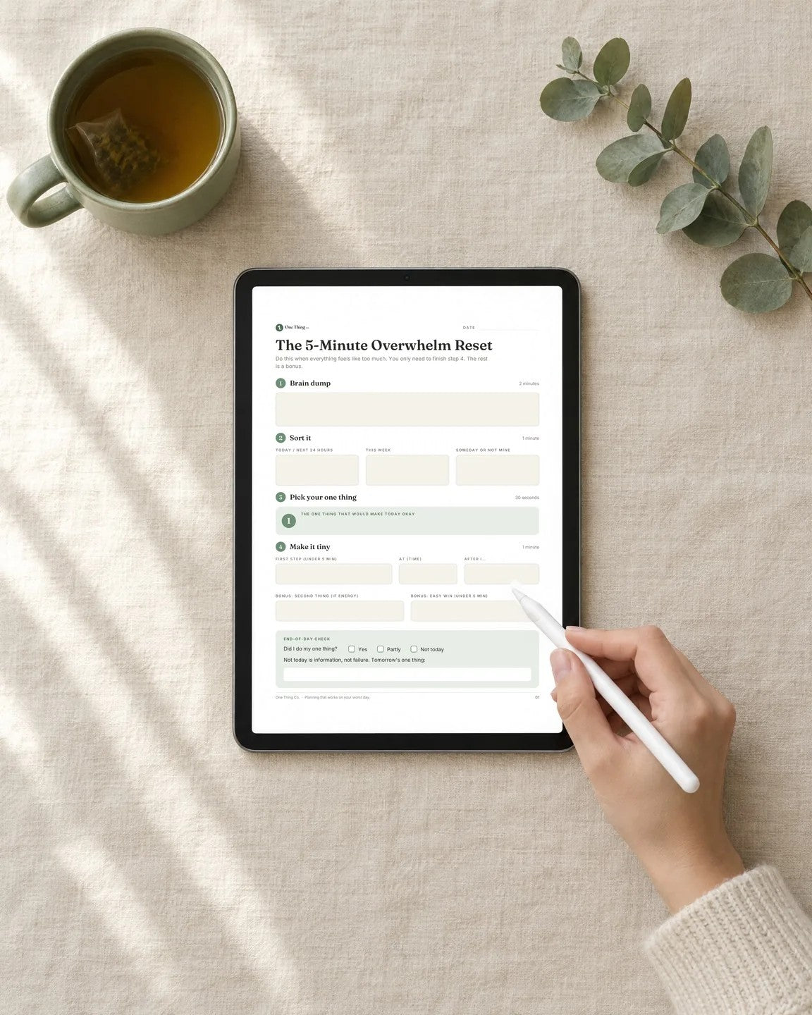 The Overwhelm Reset PDF filled in on a tablet with a stylus, next to a cup of tea